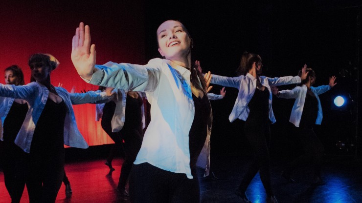 A group of dancers onstage with their arms stretched out during a performance on the Main Stage. 