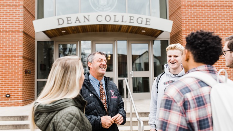 A professor speaks to four students outside of the Dean College Campus Center. 