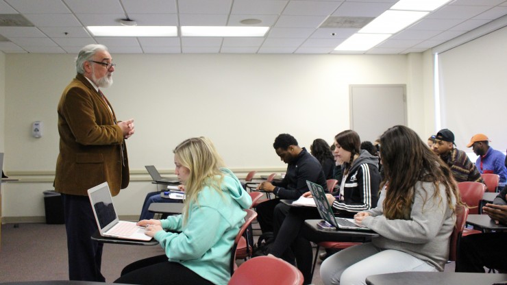 A professor gives his lecture to a group of students while they are taking notes in a Dean College classroom.