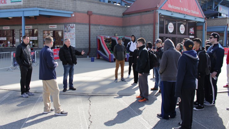 A group of students listen to a professor speak while outside of McCoy Stadium, home of the Pawtucket Red Sox.