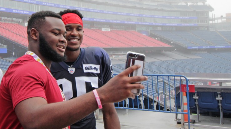 A student takes a photo with a New England Patriots player while attending Patriots Training Camp at Gillette Stadium.