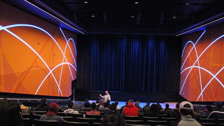 A group of students listen to a speaker while on a tour of the Basketball Hall of Fame. 