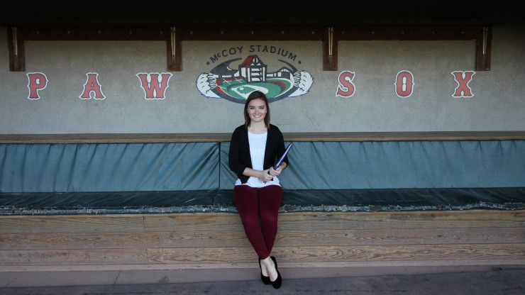 A student sits on a bench in the dugout at McCoy Stadium, home of the Paw Sox.