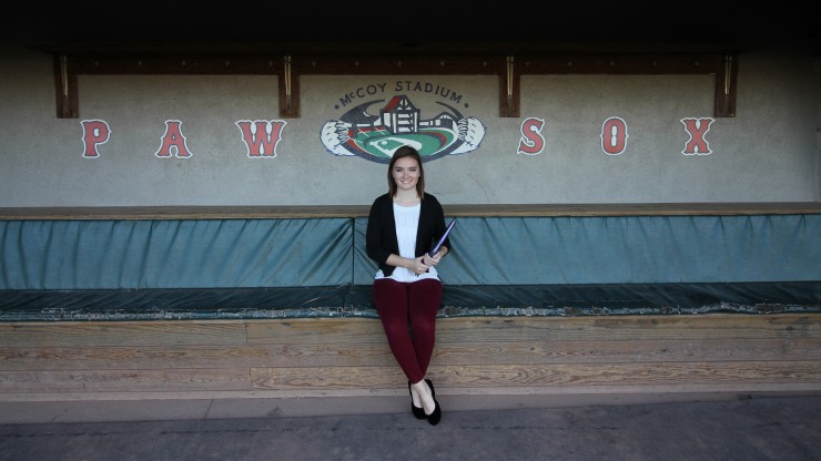 A student sitting in the dugout at McCoy Stadium, home of the Pawtucket Red Sox.