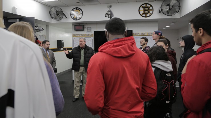 A professor speaks to a group of students while inside the Providence Bruins locker room during a tour of the Dunkin Donuts Center.