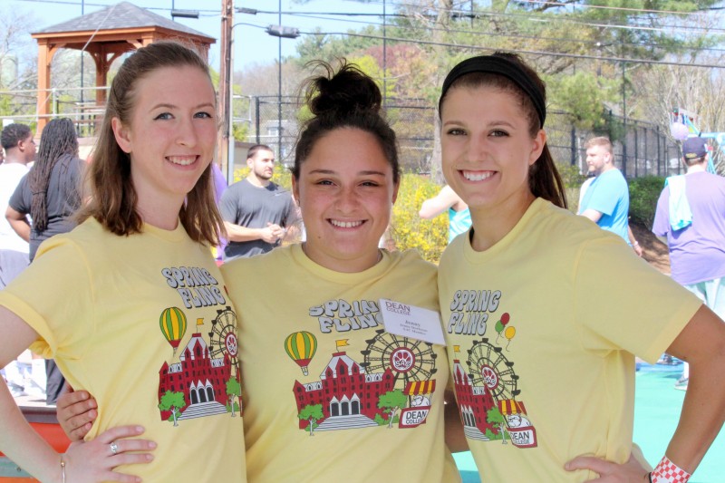 three students smiling while at the spring fling event on campus. 