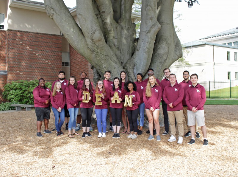 a group of students standing outside holding letters that spell out the word dean